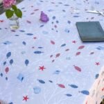 Nappe polyester Moana – motif marin poissons, étoiles de mer et coraux, coloris beige ou bleu, disponible en ronde, ovale, carrée ou rectangulaire