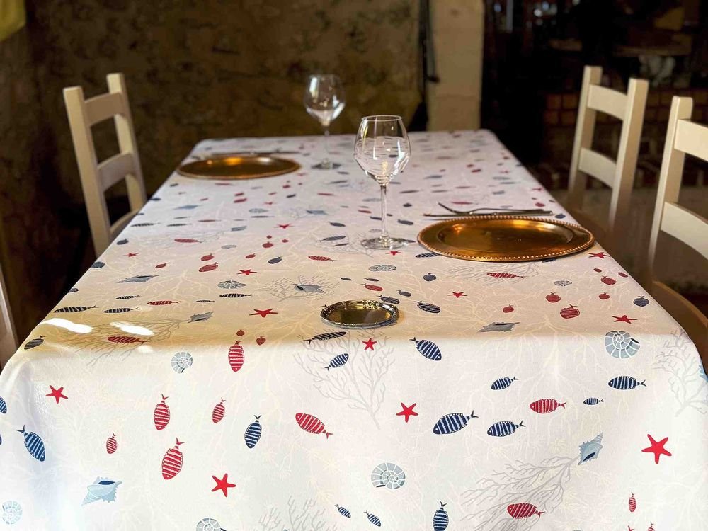 Nappe polyester Moana – motif marin poissons, étoiles de mer et coraux, coloris beige ou bleu, disponible en ronde, ovale, carrée ou rectangulaire