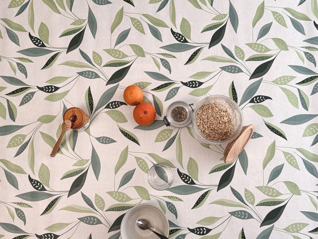 Toile cirée Class Amande – motif feuillage stylisé vert amande et sauge sur fond écru, largeur 140 cm