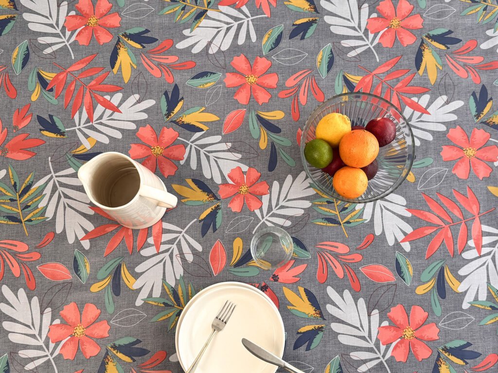 Toile cirée florale Emma Bleu – fleurs rouge corail et feuillages multicolores sur fond gris bleuté, largeur 140 cm
