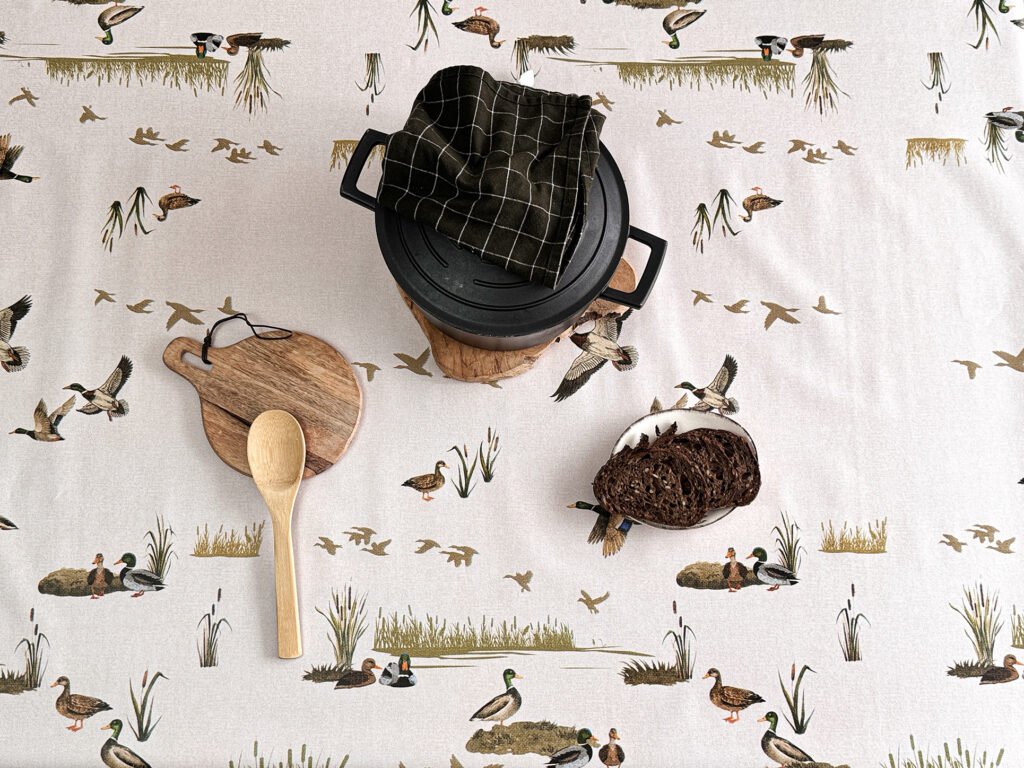 Toile cirée Étang – motif canards, roseaux et paysage lacustre, tons beige et vert olive, largeur 140 cm