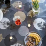 Toile cirée Nasseau Or 160 cm – motif cercles graphiques et feuilles tropicales stylisées en doré mat gris anthracite et blanc cassé, imperméable, vendue au mètre ou sur mesure toutes formes