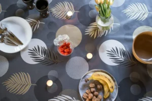 Toile cirée Nasseau Or 160 cm – motif cercles graphiques et feuilles tropicales stylisées en doré mat gris anthracite et blanc cassé, imperméable, vendue au mètre ou sur mesure toutes formes