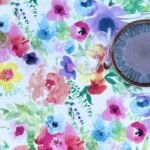 Toile cirée Printemps ronde 160 cm – imprimé floral multicolore façon aquarelle sur fond clair, finition biais renforcé`