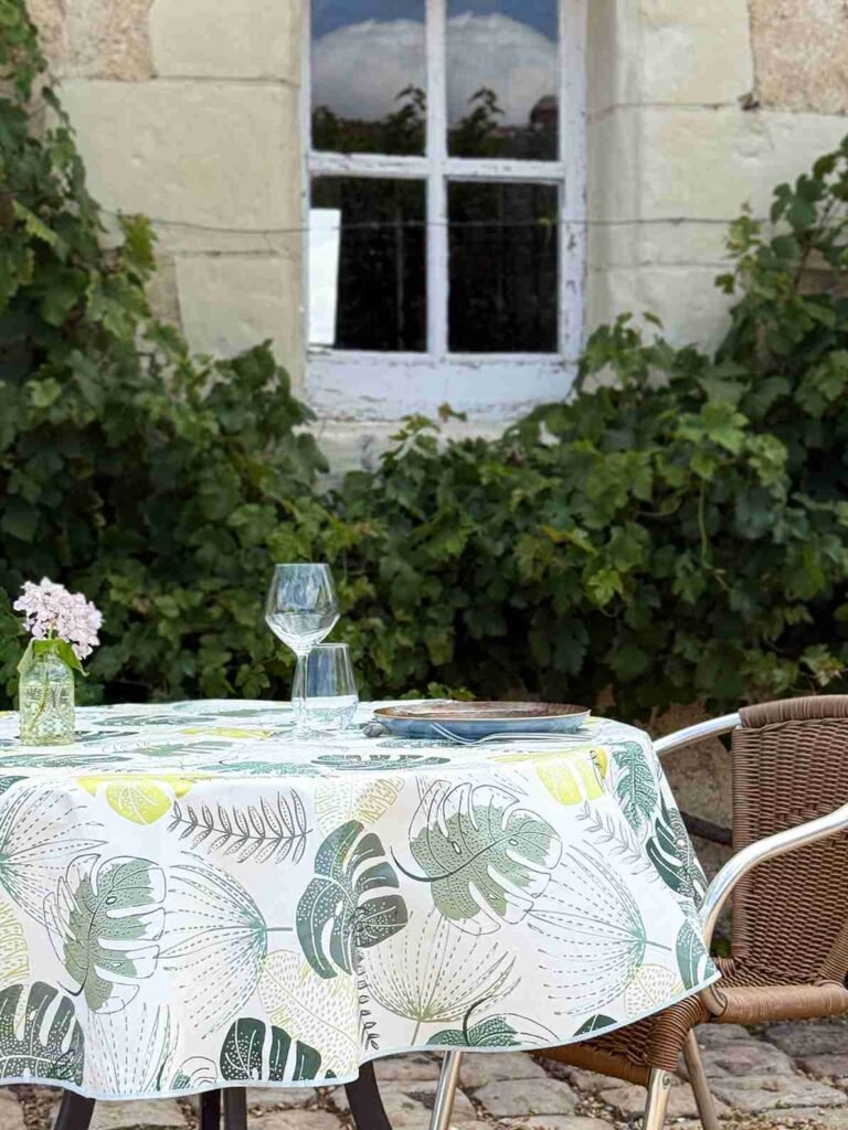 Toile cirée Tadao ronde 160 cm – motif feuillage tropical vert et jaune sur fond blanc, finition biais renforcé