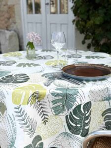 Toile cirée Tadao ronde 160 cm – motif feuillage tropical vert et jaune sur fond blanc, finition biais renforcé