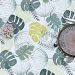Toile cirée Tadao ronde 160 cm – motif feuillage tropical vert et jaune sur fond blanc, finition biais renforcé