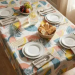 Toile cirée déco Printanière 140 cm – grandes feuilles de palmier et monstera en rose corail, bleu canard et jaune soleil sur fond blanc, vendue au mètre ou sur mesure