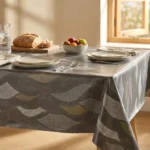 Toile cirée déco Sabine 140 cm – grandes feuilles lancéolées gris argent et or kaki sur fond anthracite texturé, vendue au mètre ou sur mesure