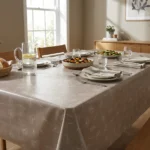 Toile cirée déco Sophie Beige 180 cm – aigrettes de pissenlit nacrées sur fond taupe chaud, vendue au mètre ou sur mesure