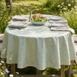 Toile cirée coton molletonné Sophie Vert 160 cm – silhouettes de pissenlit en blanc nacré sur fond vert céladon