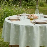 Toile cirée coton molletonné Sophie Vert 160 cm – silhouettes de pissenlit en blanc nacré sur fond vert céladon