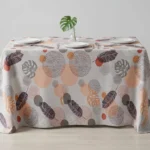 Nappe polyester tropicale Illana coloris beige rosé – plumes et feuilles de monstera