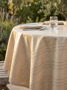 Toile cirée déco Riviera beige sur table ronde dressée – rayures fines argentées sur fond beige sable effet lin, ambiance intérieur chaleureux