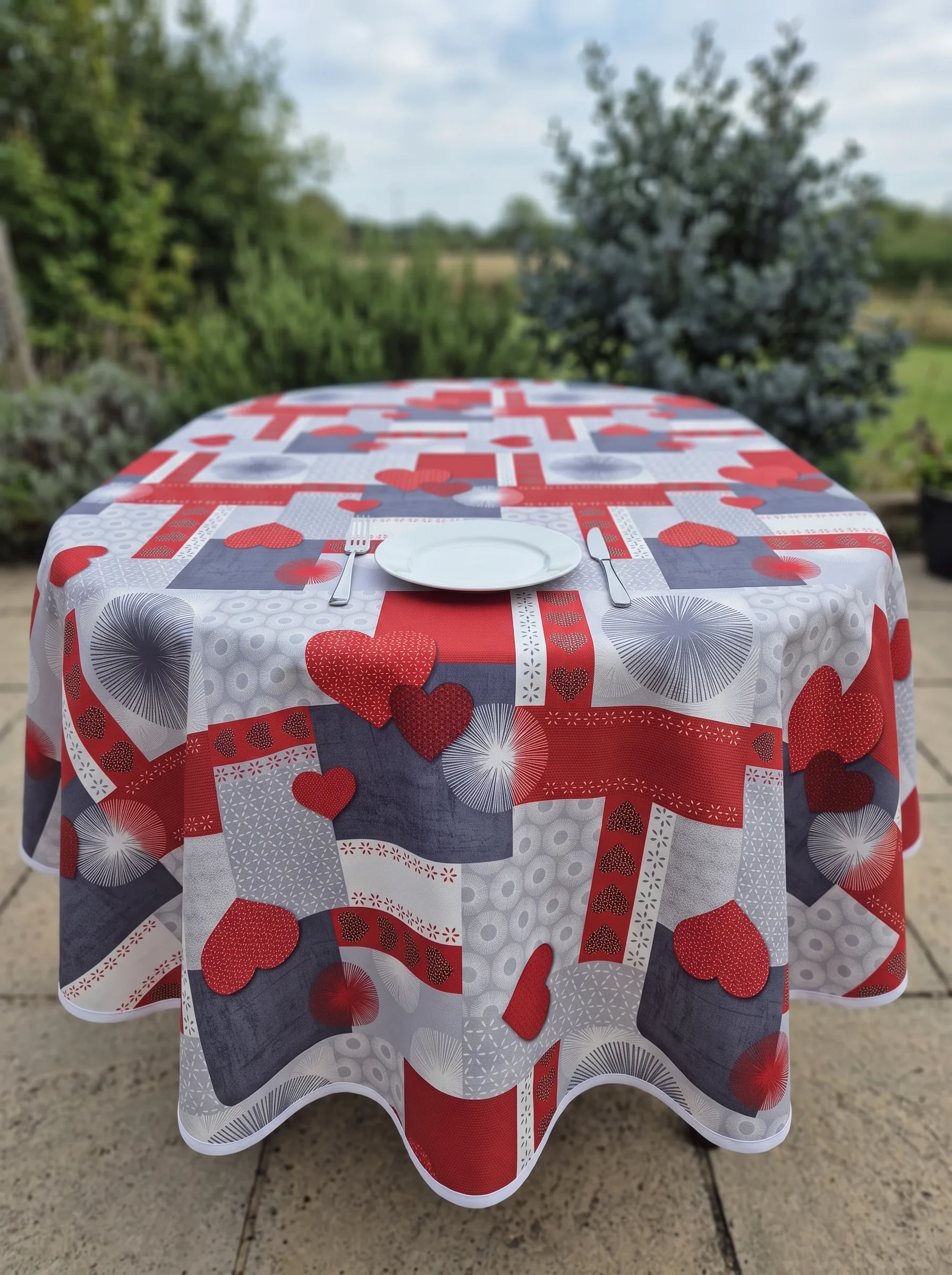Nappe polyester sur mesure Estelle rouge ovale en terrasse – motif cœurs rouge et gris