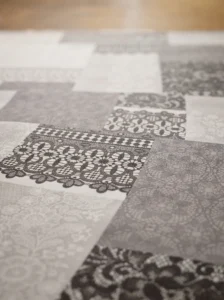 Détail du motif patchwork dentelle et broderie gris anthracite et blanc sur fond gris perle – toile cirée molletonné Dentelière gris